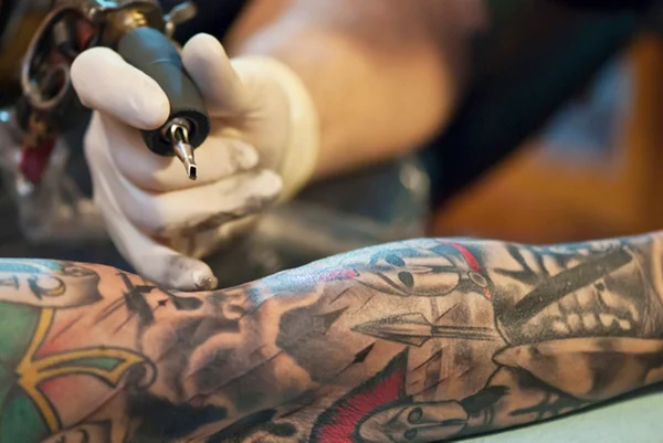 Tatuador fazendo tatuagem em braço - Metrópoles