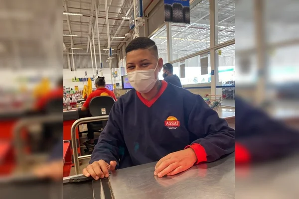 Homem de máscara e camisa de manga comprida azul em caixa de supermercado