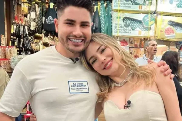 Foto colorida de Rachel Sheherazade e Lucas Sousa, vestindo camisas brancas e abraçados, ao fundo, um mercado - Metrópoles