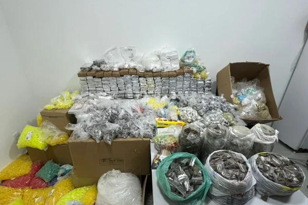 Imagem colorida de caixas de papelão e sacos plásticos coloridos armazenados em uma refinaria de tráfico com diferentes tipos de drogas. - Metrópoles