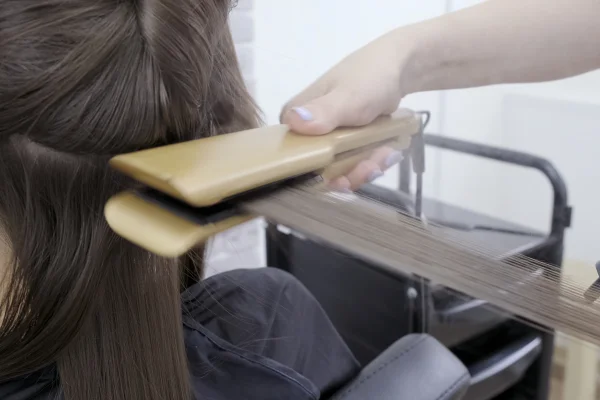 Foto de cabelereira alisando cabelo - Metrópoles