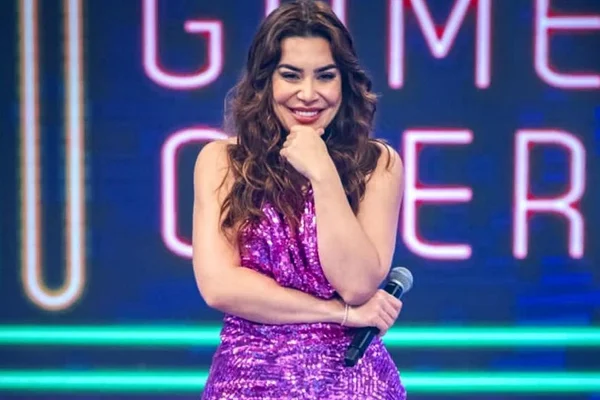Naiara Azevedo de vestido rosa segurando microfone e com a mao no queixo