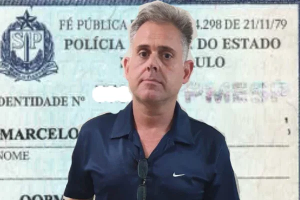 Homem branco com camise azul, sem barba e de cabelos grisalhos. Ao fundo, reprodução de uma carteira funcional da PM de São Paulo - Metrópoles