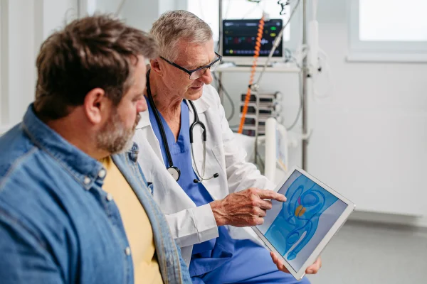 Foto de médico mostrando ilustração de próstata para paciente - Metrópoles