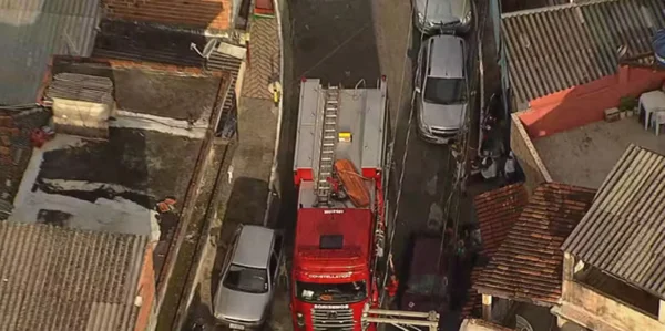 Imagem aérea colorida de viela com caminhão de bombeiros e veículos estacionados