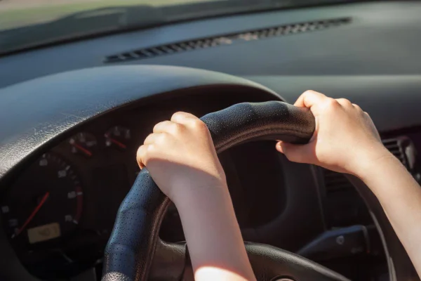 Criança dirigindo. Mãos ao volante do carro - Metrópoles