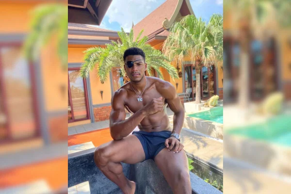 Imagem colorida de jovem usando tapa olho sentado na beira da piscina - Metrópoles