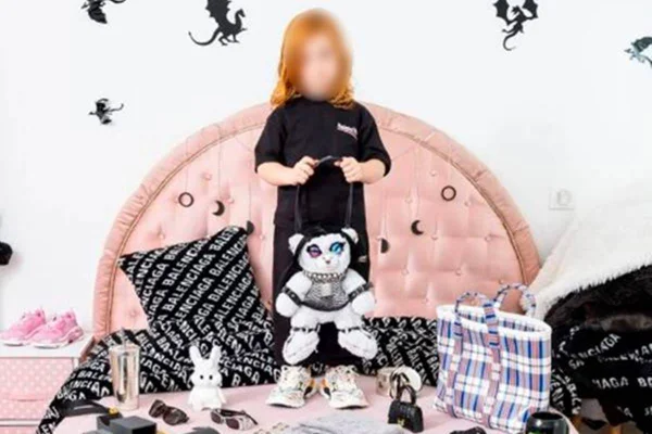 Criança em pé na cama segurando uma bolsa de pelúcia