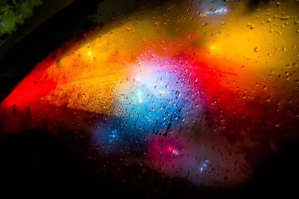 Foto colorida do vidro de um carro embaçado com luzes coloridas - Metrópoles