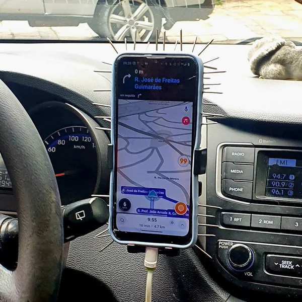 Imagem colorida mostra aparelho celular em um suporte dentro de carro com pregos ao redor da capinha, com o objetivo de evitar roubos de motoristas - Metrópoles