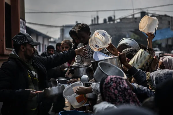 Os palestinos, durante guerra com Israel, estendem seus recipientes vazios para serem enchidos com alimentos, distribuídos por organizações de caridade em Rafah - Metrópoles