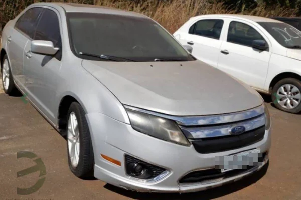 Foto colorida de carro sedan prata em pátio de leilão