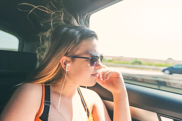 Adolescente ouvindo música no carro. Metrópoles