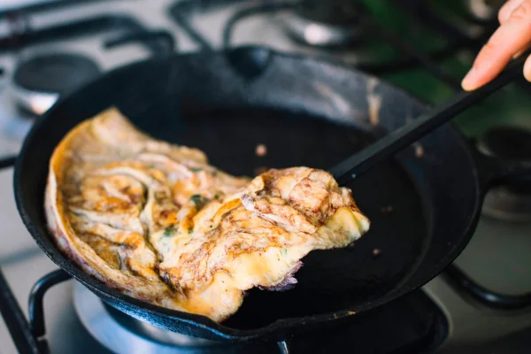 Frigideira no fogão com omelete sendo feita