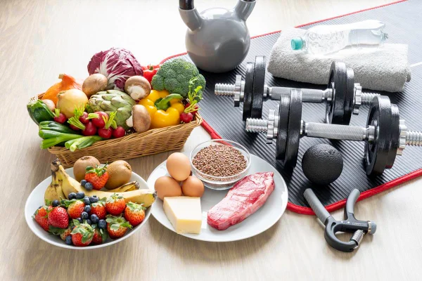 Imagem mostra pesos de academia e pratos com frutas, vegetais e carnes - Metrópoles - ganhar massa