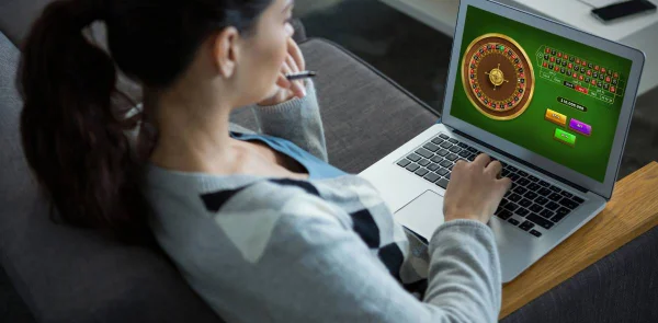 Fotografia colorida mostrando mulher jogando roleta no computador colocado sobre as pernas-Metrópoles APOSTAS