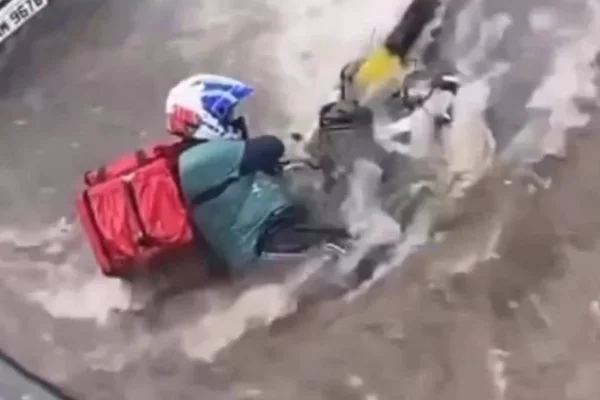 Vídeo registrado por uma mulher que trabalha na região mostra o motociclista lutando contra a força da água na avenida Olinto Meireles