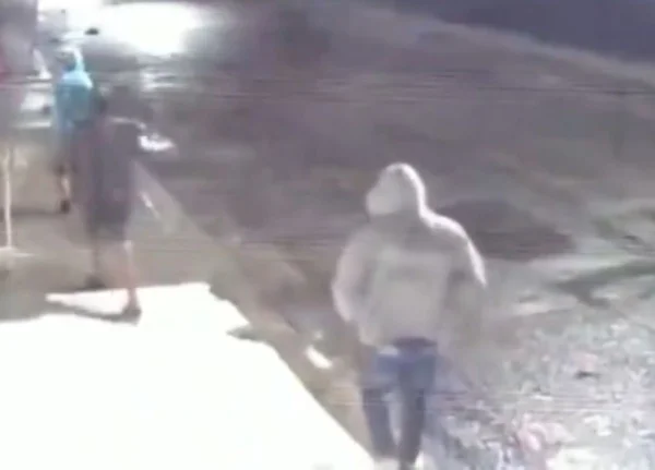 Imagem de três homens encapuzados, de costas, andando pela rua - Metrópoles