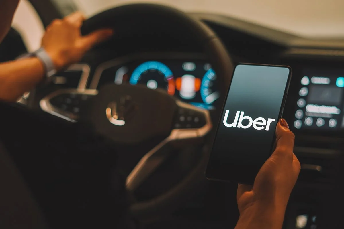 Foto colorida de mulher branca segurança um celular com o aplicativo da Uber aberto - Metrópoles