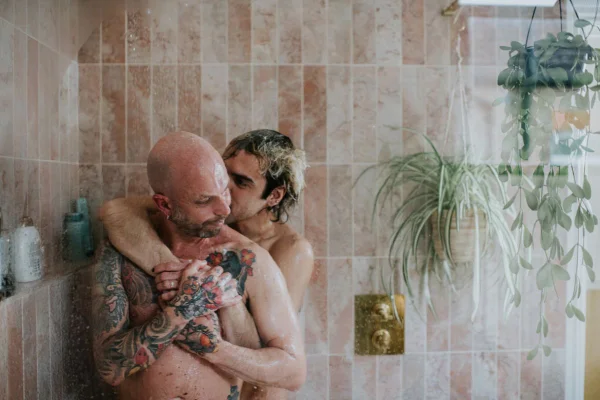 imagem colorida de um casal homossexual em um chuveiro abraçados