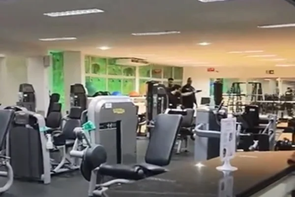 Imagem colorida de um homem apontando arma para outro em uma academia - Metrópoles