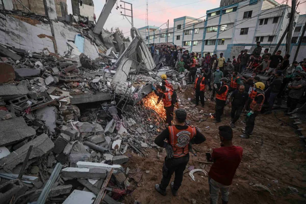 Equipes de busca e resgate participam dos esforços para resgatar civis presos sob os escombros após um ataque aéreo israelense em Khan Yunis, Gaza - Metrópoles
