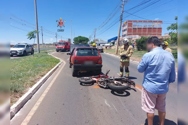 Moto caída em pista e carro vermelho à frente