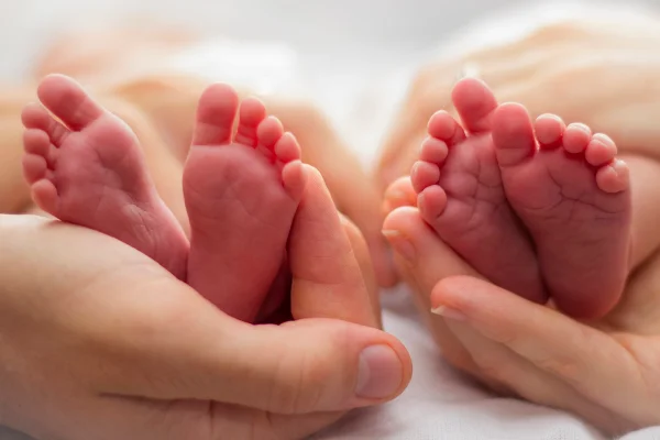 Foto mostra pai e mãe segurando os pés de bebês gêmeos. Bebês trocados, bebês gêmeos, trocados na maternidade, trocadas ao nascer