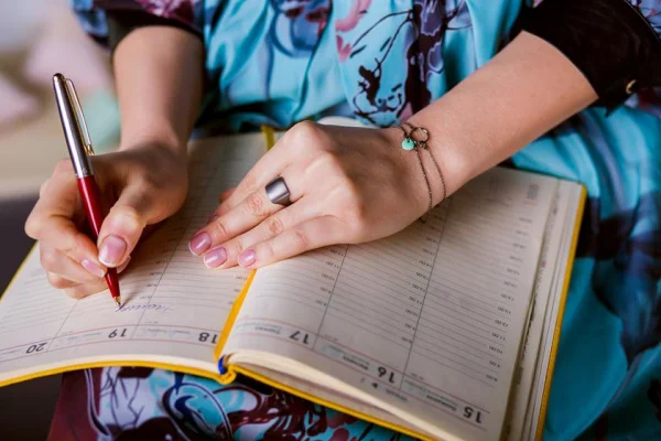 Mulher escrevendo em um caderno foto colorida