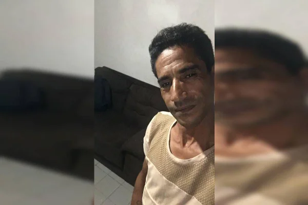 Foto colorida de homem negro com roupa bege fazendo selfie