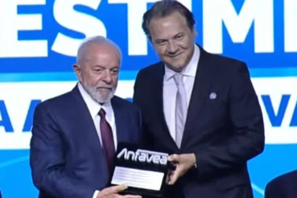 Foto colorida do presidente Luiz Inácio Lula da Silva segurando placa comemorativa ao lado do presidente da Anfavea, Márcia Lima - Metrópoles