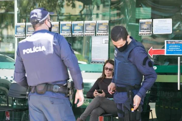 mulher e policiais na frente de delegacia