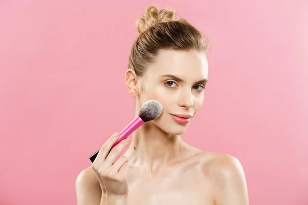 Mulher com pincel de blush no rosto