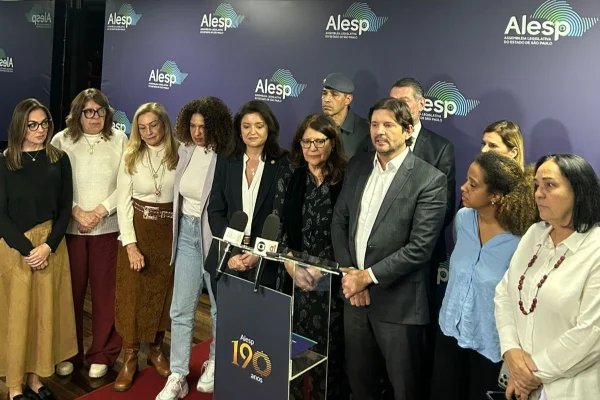 Imagens coloridas mostram deputados estaduais de SP, homens e mulheres, postados atrás de um púlpito, após entrevista coletiva na Alesp
