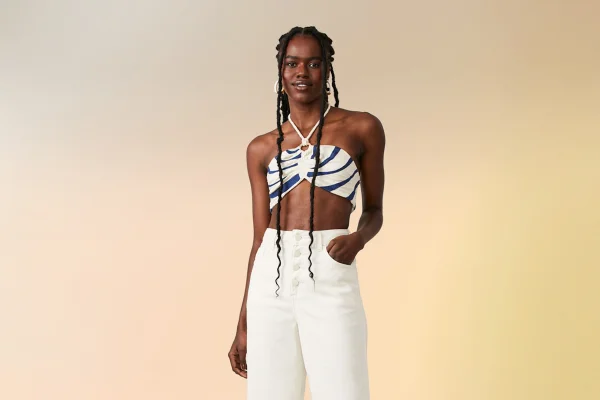 Modelo usa top estampado em azul e branco com calça branca de cintura alta - Metrópoles