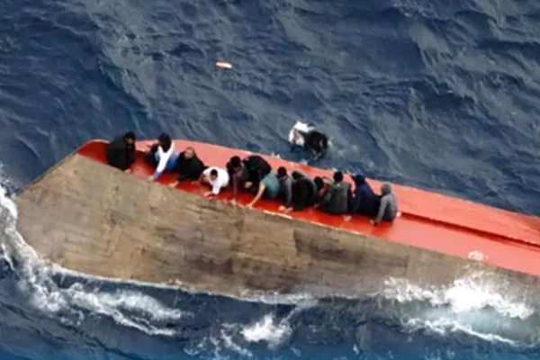 Foto colorido de sobreviventes sobre casco do barco virado - Metrópoles