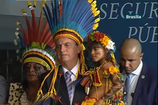 Bolsonaro com cocar e segurando criança indígena no colo