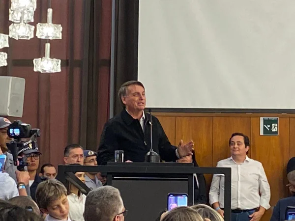 Imagem colorida de Jair Bolsonaro, de jaqueta preta, no alto de um púlpito no palco de um dos salões da Câmara Municipal de SP - Metrópoles