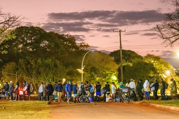 Foto colorida de pessoas em fila de abrigo emergencial do DF