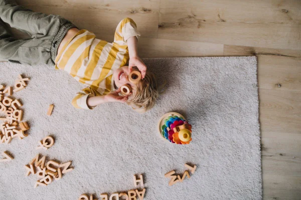 Foto colorida de criança brincando com letras no chão - Metrópoles