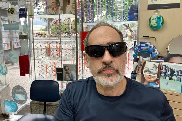 Foto colorida de homem com óculos escuros, barba branca e camiseta preta - Metrópoles