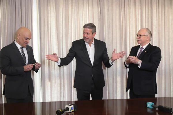 Os ministros do STF Alexandre de Moraes e Edson Fachin conversam com o deputado e presidente da Câmara Federal, Arthur Lira, entre ambos. Eles assinam acordo entre a casa legislativa e o TSE - Metrópoles