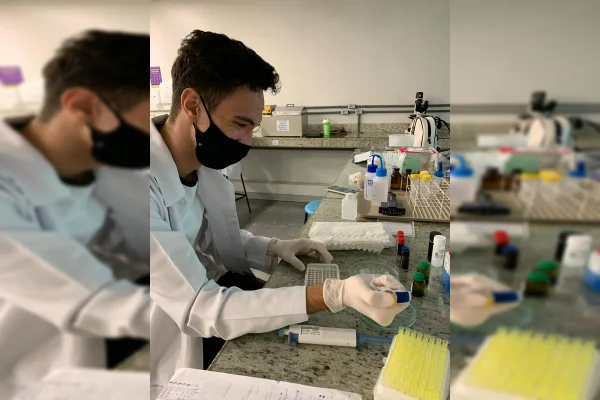Homem de mascara e luvas mexe em equipamentos de laboratório