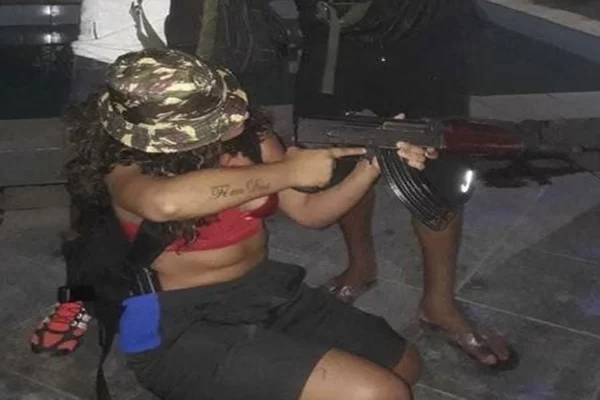 mulher agachada aponta fuzil