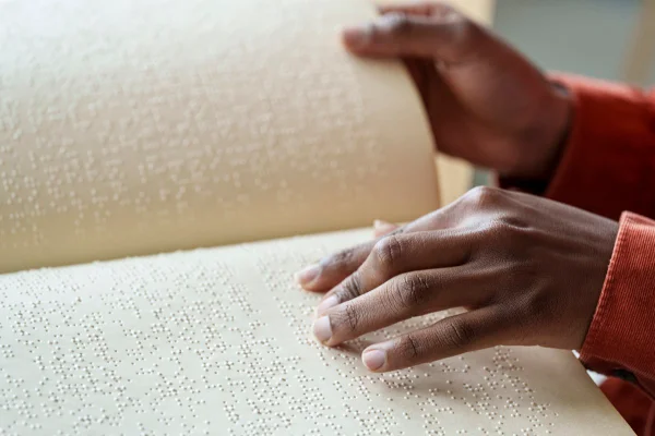 Fotografia mostra mãos de mulher lendo livro em braille - Metrópoles