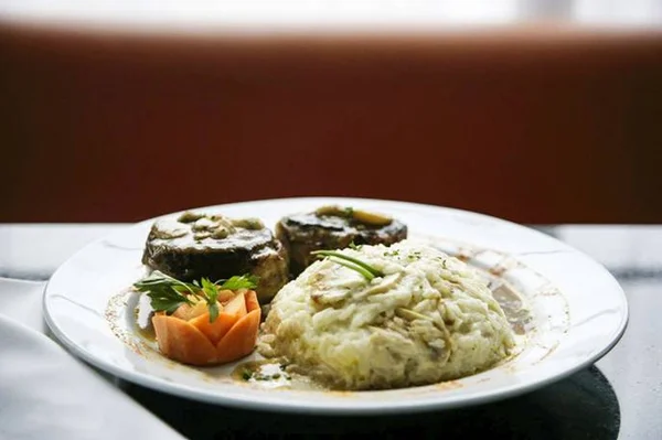 Foto de um prato branco com um arroz à piamontese, cenoura e uma pedaço de carne