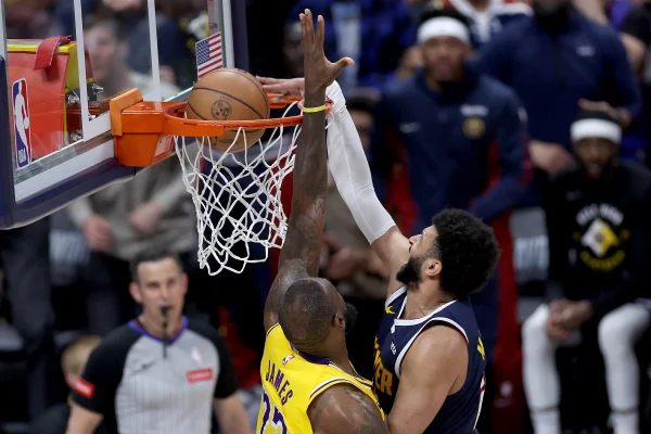 Foto colorida de Jamal Murray enterrando em LeBron - Metrópoles