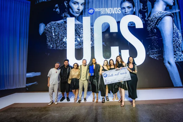 A imagem mostra diversas pessoas juntas segurando um cheque de R$ 20 mil