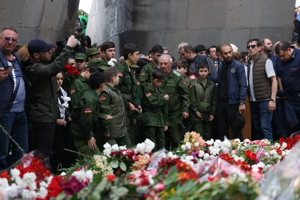 Imagem colorida mostra pessoas depositando flores na chama eterna do memorial do genocídio armênio - Metrópoles