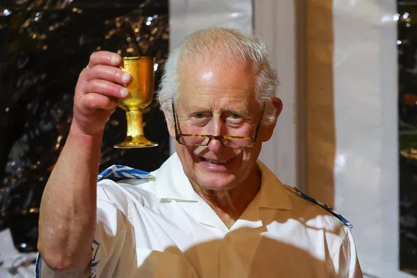 Foto colorida de homem com óculos segurando um cálice dourado - Metrópoles